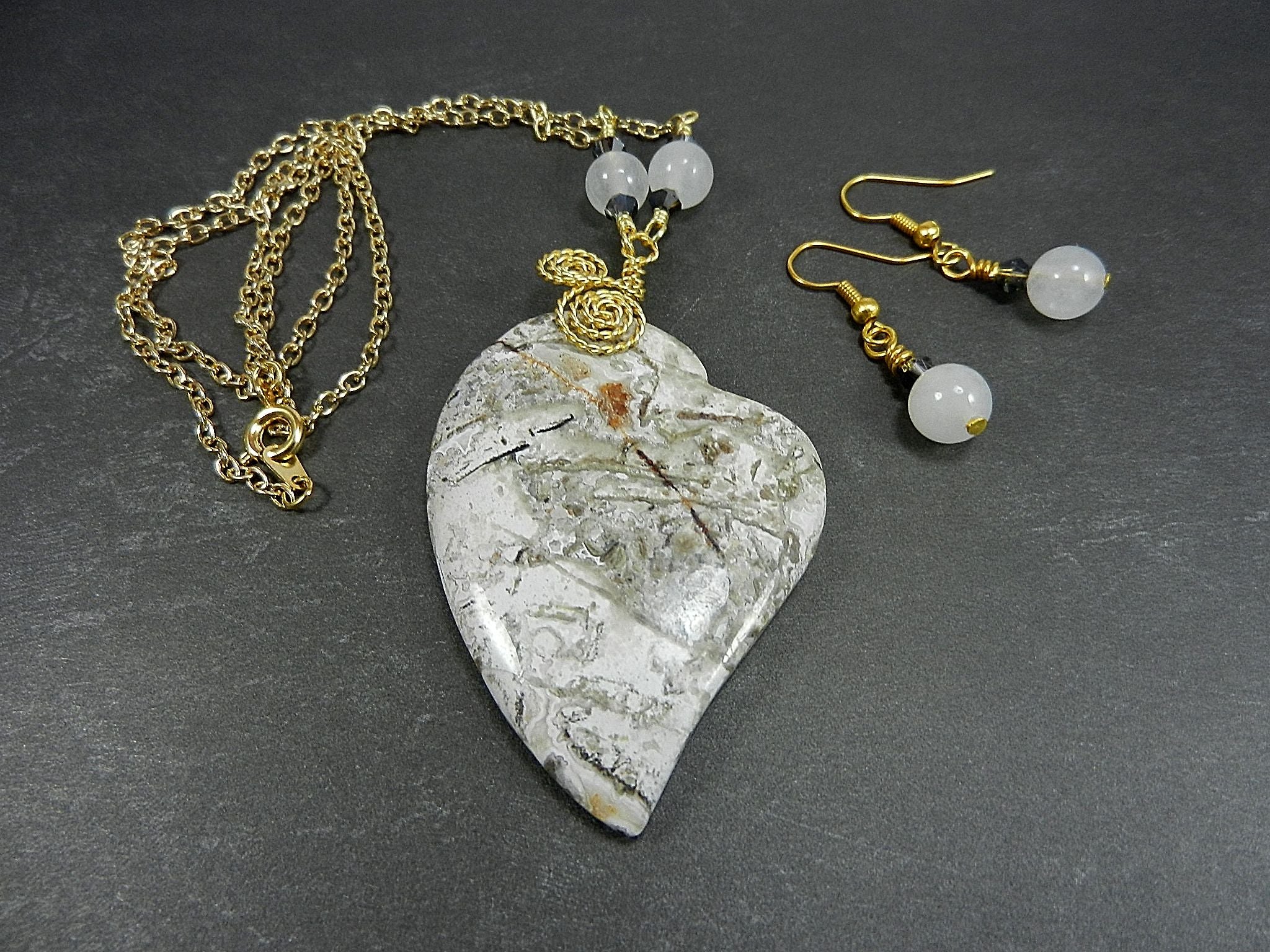 Tree Agate Heart Shaped Gemstone Pendant Gold Wire Wrapped with a White Background and Green and Grey Lines with Matching Earrings